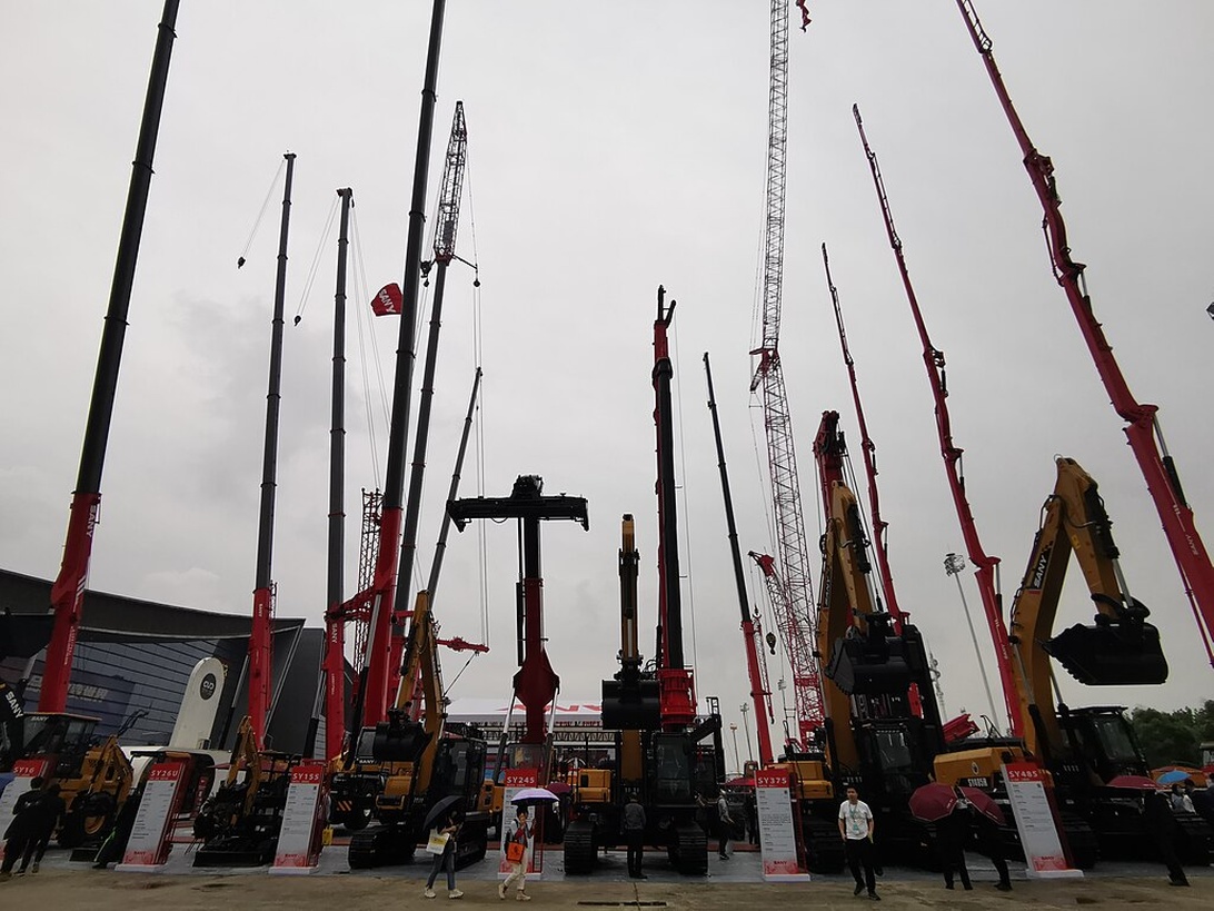 Eine belebte Baustelle mit einem Bagger im Vordergrund, der die Symphonie des Fortschritts darstellt.